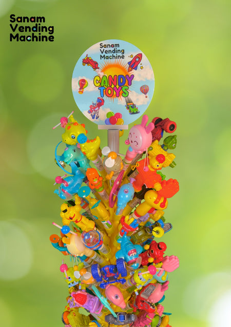 Colorful candy toy display with 'Sanam Vending Machine' branding against a green blurred background.