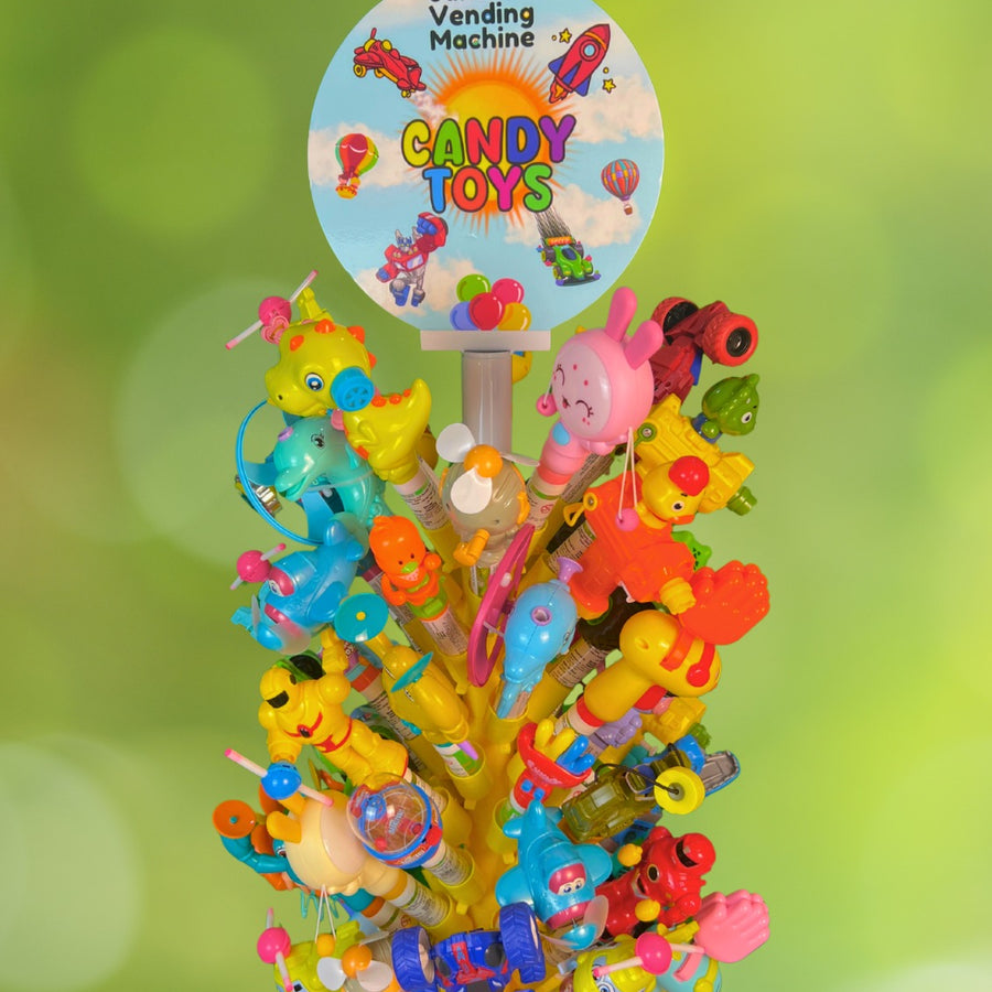 Colorful candy toy display with 'Sanam Vending Machine' branding against a green blurred background.